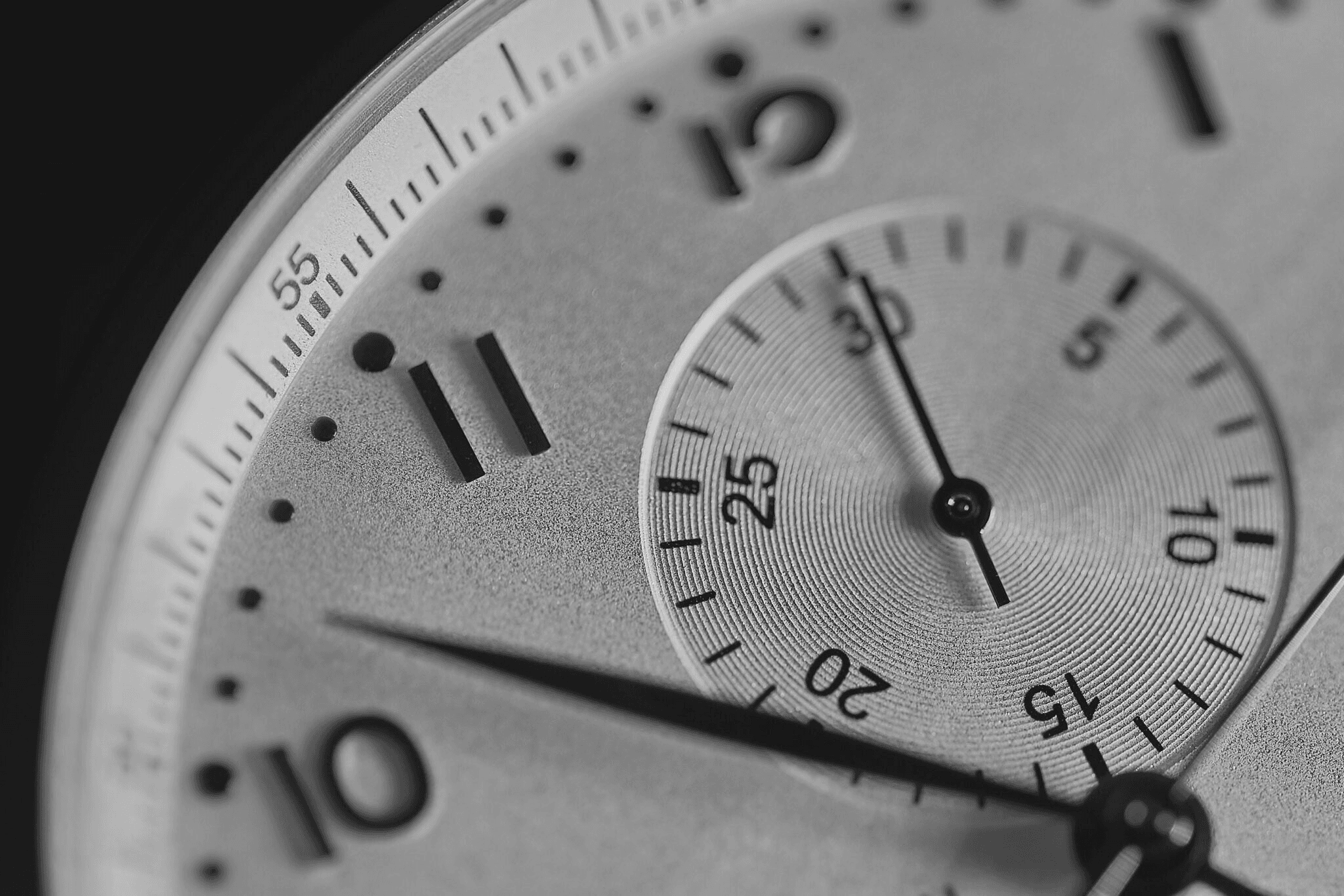 Macro black-and-white close-up of a luxury watch face with sub-dial and textured surface.