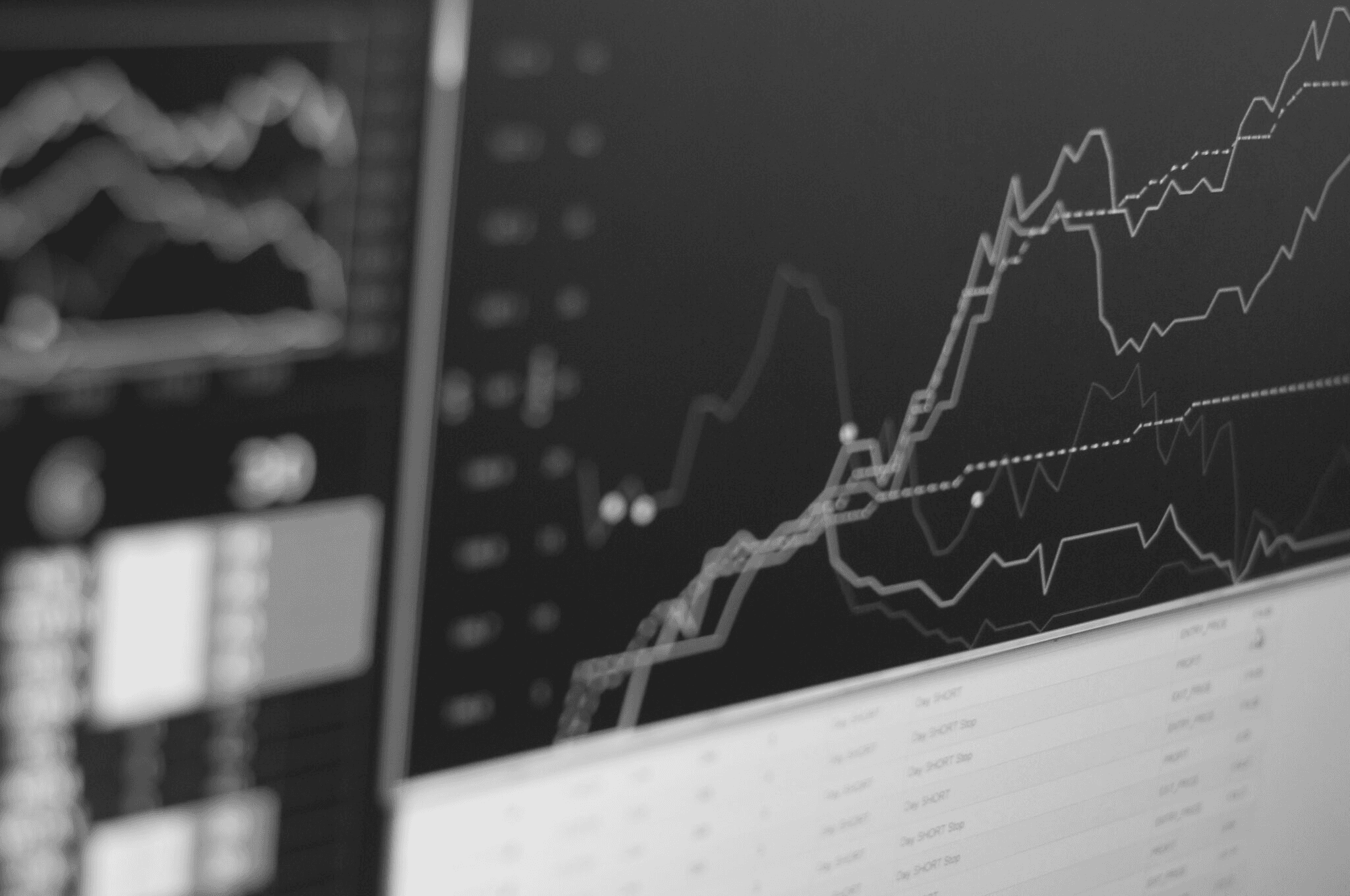 Black-and-white close-up of a screen showing financial charts and market data.
