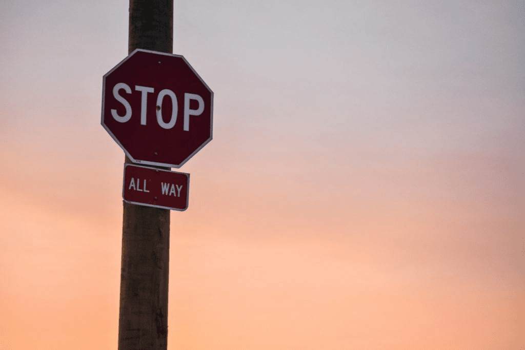 Stop sign on a pole against a soft sunset sky.